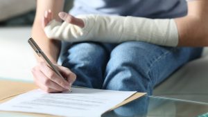 Disabled woman with bandaged arm signing document