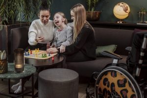 Familia con niña con incapacidad con un juego de mesa en el salón.