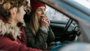Dos chicas antes de conducir se calientan se calientan las manos en el coche.