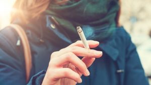 Una joven fumando en la calle.