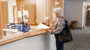 Nurse assisting a senior patient at the hospital reception desk