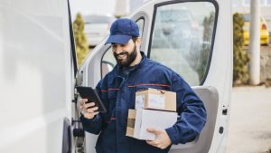 Delivery man with a parcel box in the car. - Stock image... Save