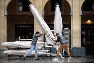 Varios camareros moviendo la sombrilla de la terraza.