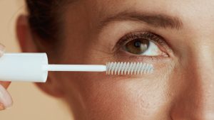 Una chica peinándose las pestañas con un bupillón.