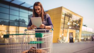 alimentación mercadona Una chica junto al carrito de la compra comprobando la multa en el supermercado.