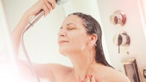 Una chica intentando pensar ideas originales bajo una ducha de agua caliente.