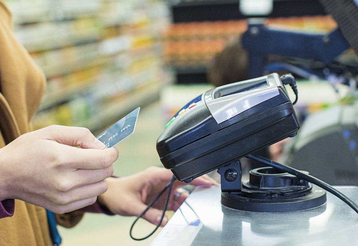 Una mujer pagando con tarjeta en el supermercado.