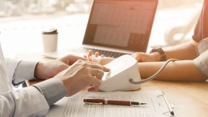 Doctor pressing pressure blood gauge button and talking to patient.