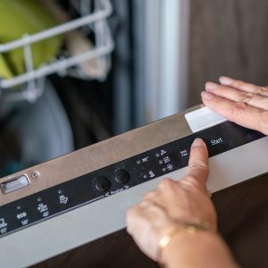 Close-up of woman setting cycle on dishwasher