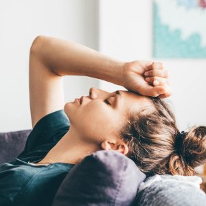 Sad and depressed woman sitting on sofa at home.