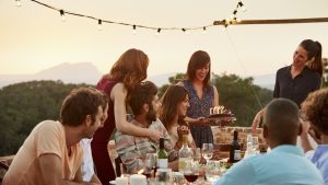Woman carrying cake by friends at table