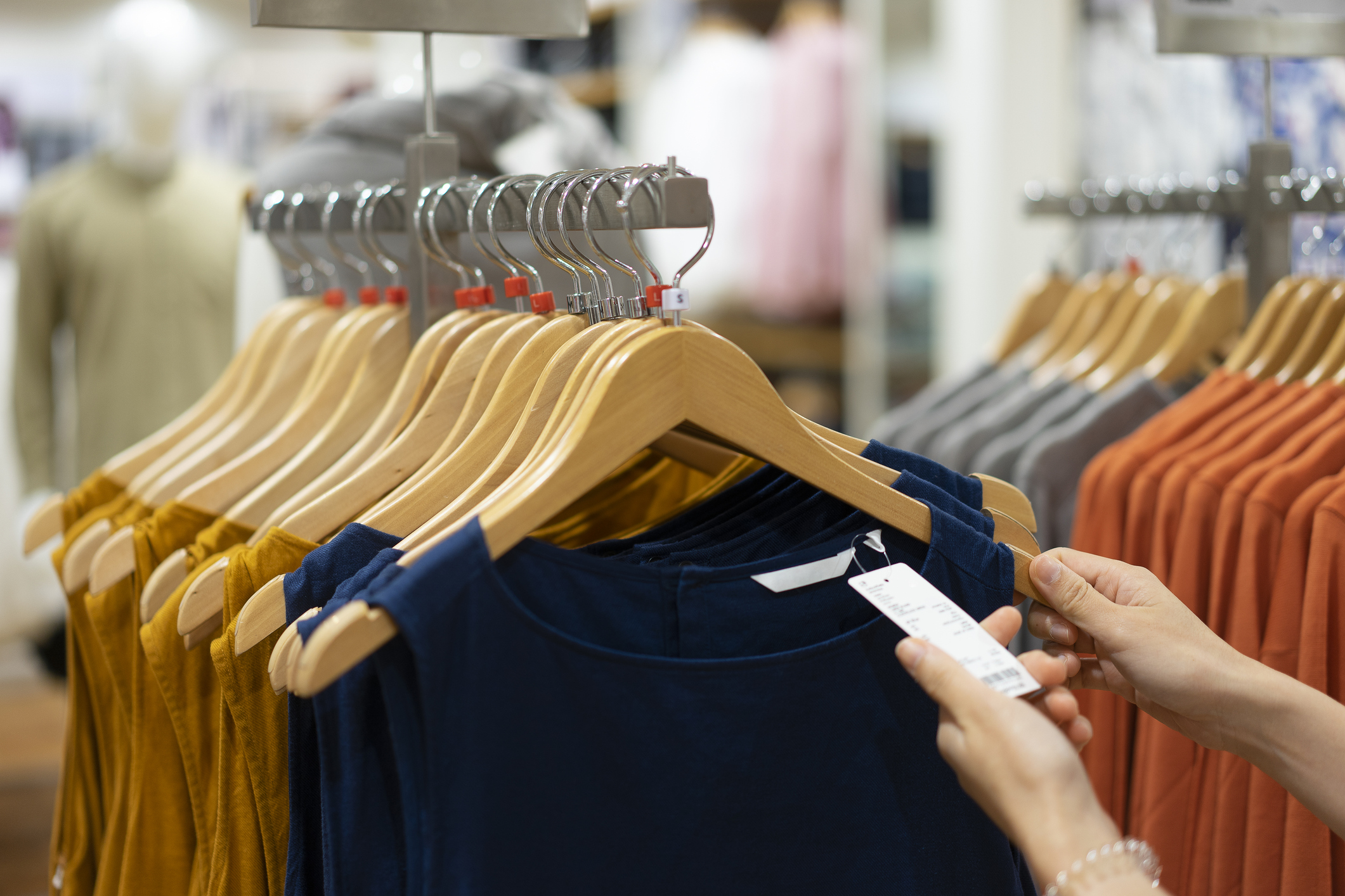 Una persona observa la etiqueta de una prenda de ropa en una tienda.