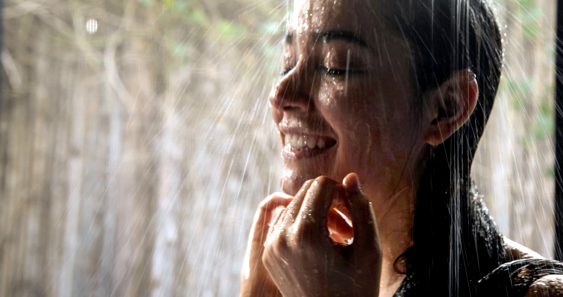 Una persona sonríe mientras se da una ducha.