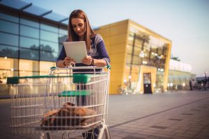Una chica junto al carrito de la compra comprobando la multa en el supermercado mitos alimentación