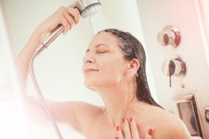 Una chica intentando pensar ideas originales bajo una ducha de agua caliente.