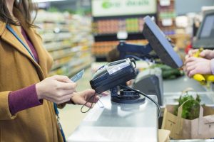Una mujer pagando con tarjeta en el supermercado banco