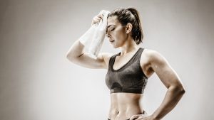 Caucasian woman wiping sweat from forehead