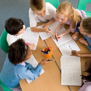 Children (7-12) sitting around table, having discussion, elevated view