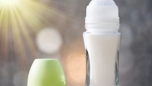 Glass deodorant container with roll illuminated by rays of sunlight.