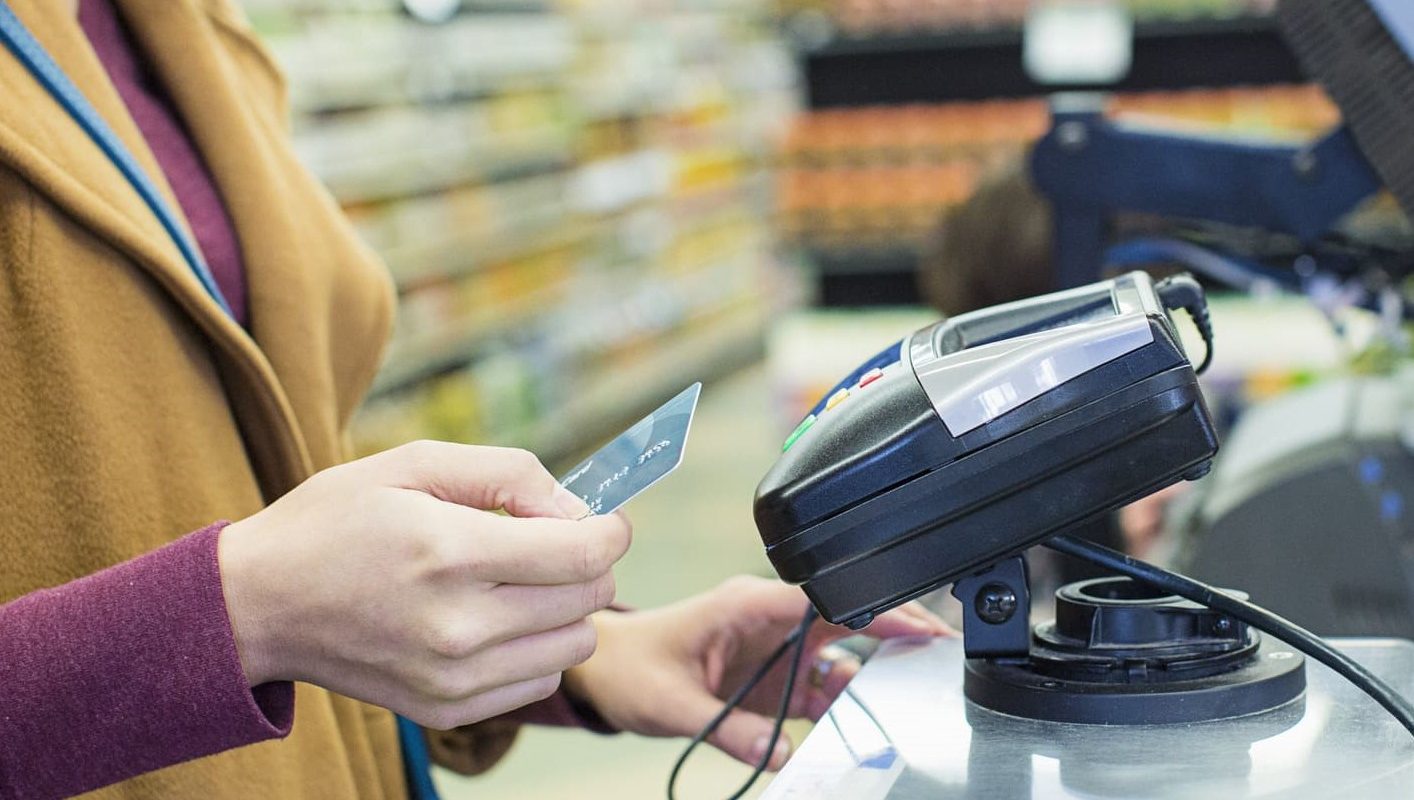 Una mujer pagando con tarjeta en el supermercado.