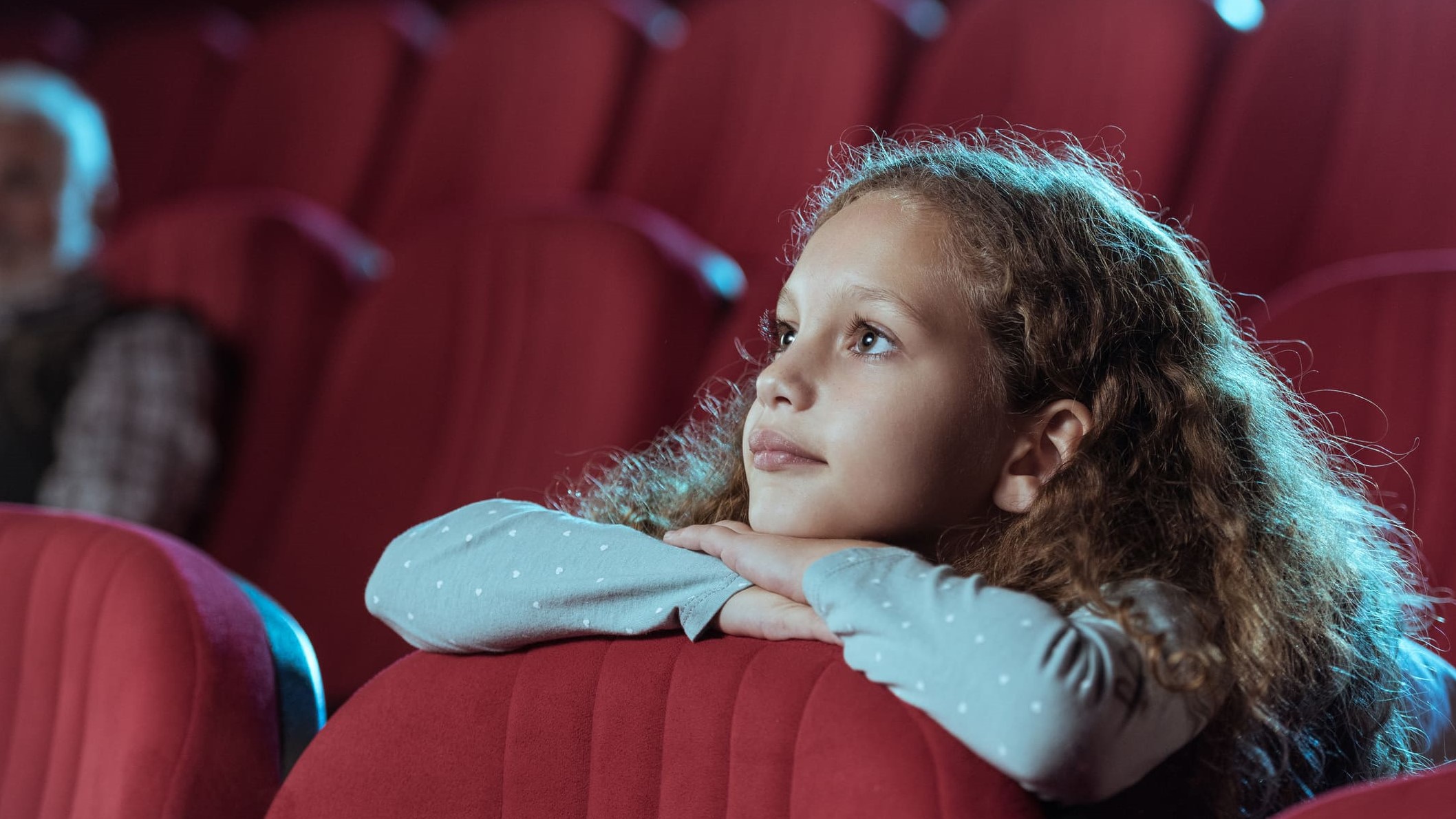 Una niña observa atentamente la pantalla en una sala de cine.