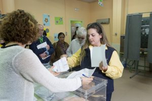 Una empleada de Correos depositando su voto en la urna electoral.