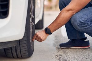 Un conductor mirando la presión de los neumáticos de su coche antes de disfrutar de la Semana Santa.