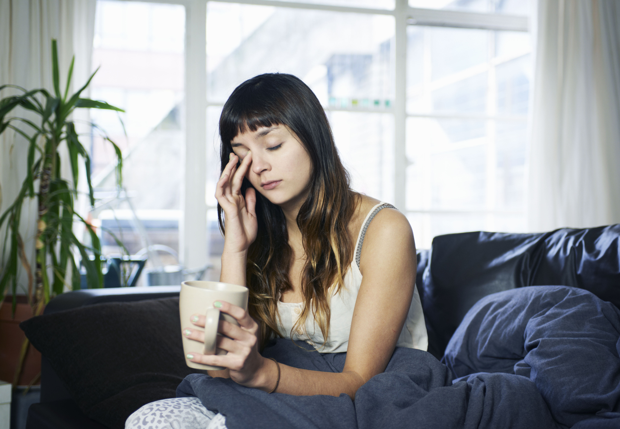 Una chica intentando combatir el cansancio con un café.