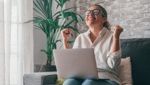 Young Woman Using Laptop While Sitting On Sofa At Home