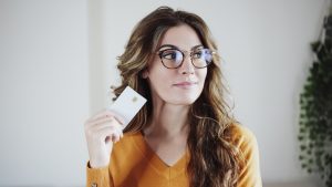 Beautiful woman with eyeglasses holding credit card at home