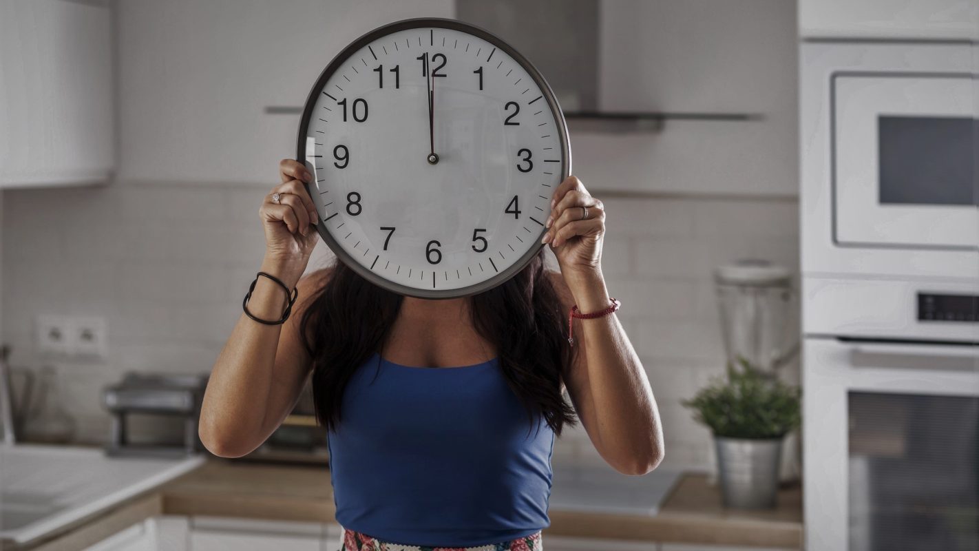 Una chica cogiendo el reloj a las 00:00 horas.