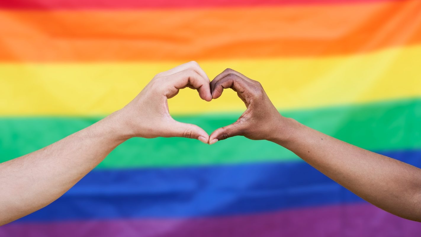 Dos personas haciendo un corazón con las manos luchando con la homofobia, la transfobia y la bifobia.
