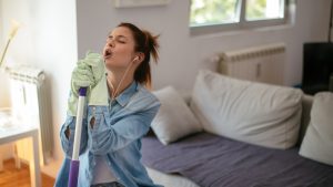 Happy woman singing while cleaning house