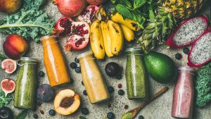 Colorful smoothies in bottles with fresh tropical fruit and superfoods