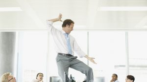 Businessman dancing on desk in cubicle