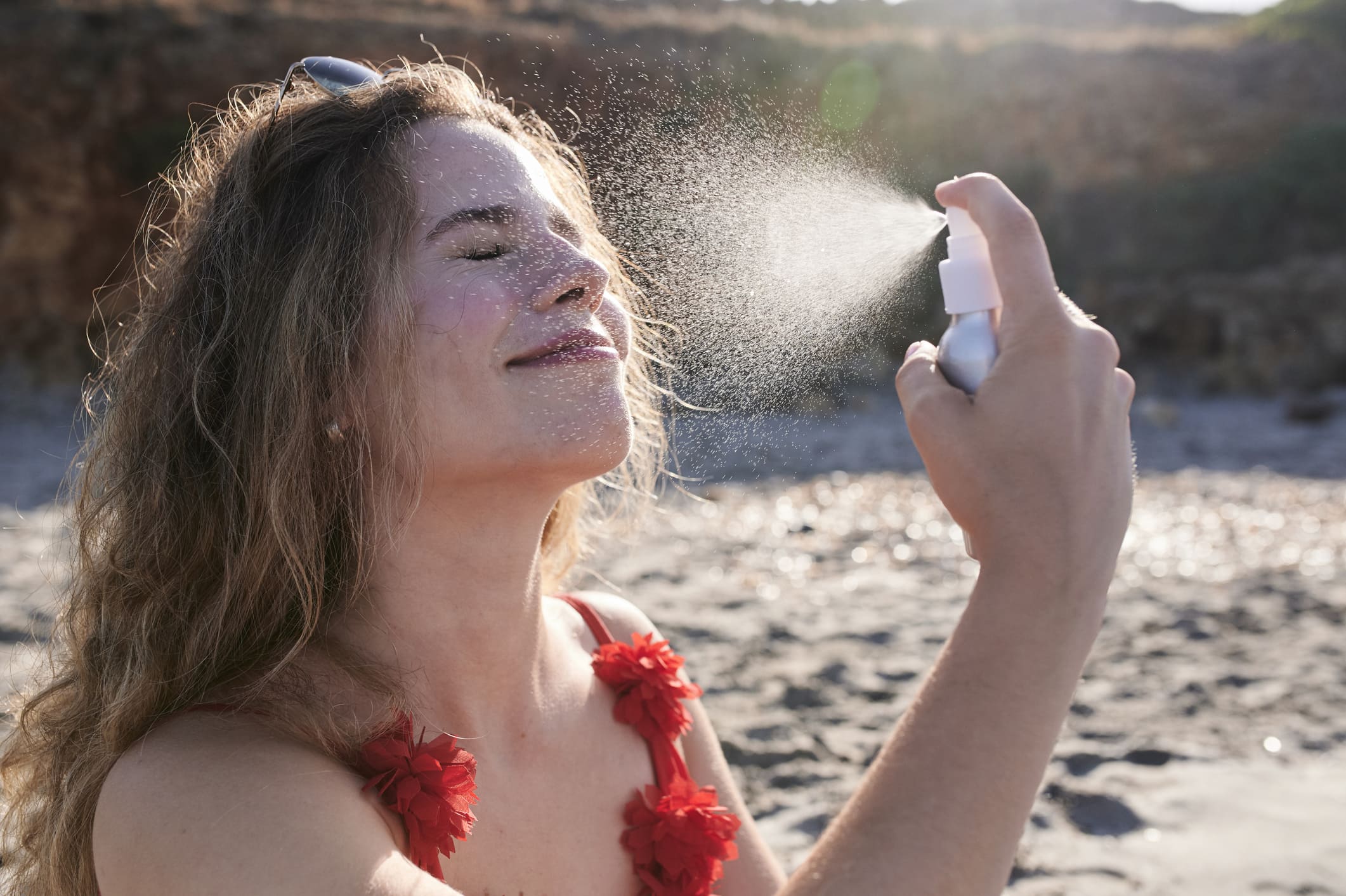 Una chica poniéndose cema solar en la playa.