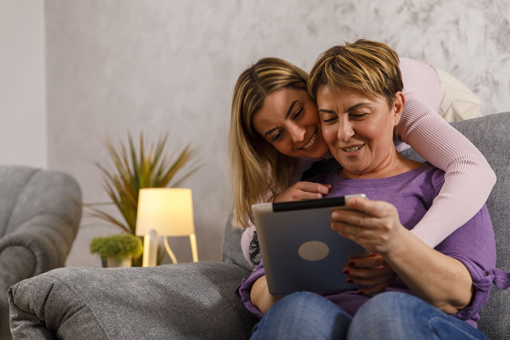 Madre e hija abrazándose y mirando juntas la tablet.