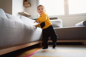 Un niño empieza a andar apoyándose en el sofá.