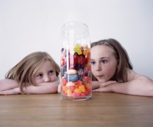 Dos niñas pequeñas contemplan las chuches que hay almacenadas en un tarro.