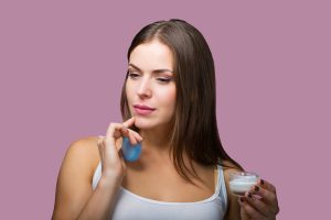 Una mujer sorprendida con los beneficios de la crema que se pone en la cara.