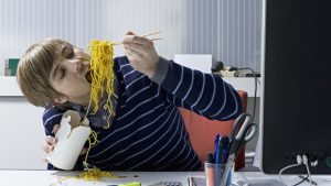 Un chico con mucho estrés come alimentos poco saludables.