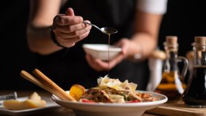 A female chef pouring sauce on salad