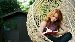 Woman writing in journal on swing seat outside