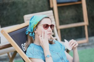 Una joven poniéndose protección solar en la piel inlcuso en un día nublado.
