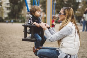 Una chica jugando con el niño pequeño en el parque infantil.