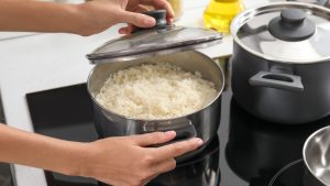 Woman cooking rice on stove in kitchen