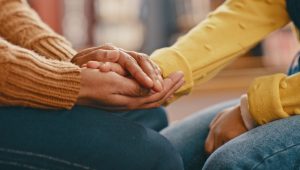 Hands, love and care touching in support, trust or unity for community, compassion or understanding. People holding hands in respect for loss, affection or passion for listening, talk or time