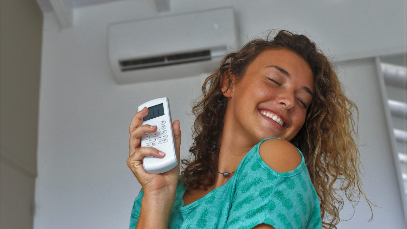 Una chica feliz por tener su casa fresquita con el aire acondicionado.
