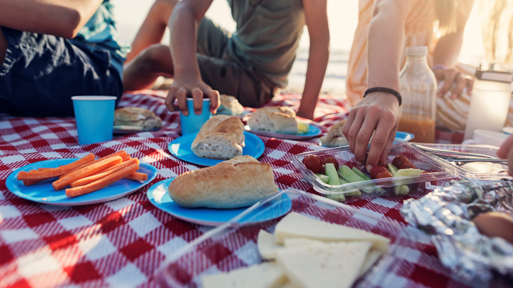 Una familia disfruta de un picnic con diferente tipo de comida en plena playa.
