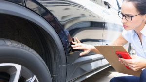 Insurance agent filling out insurance form near damaged black car